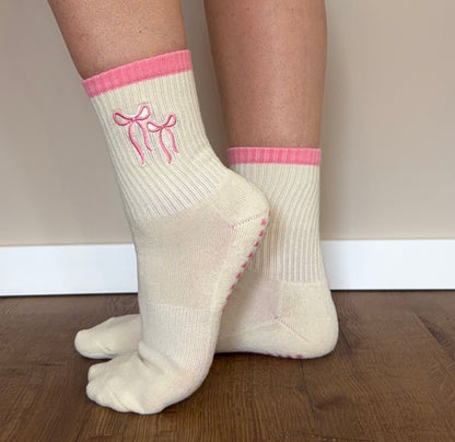 Frau trägt Pink Bow Pilates Grip Socken von Lini beim Reformer Pilates